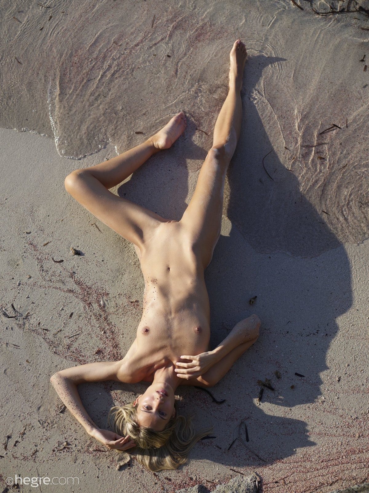 Тощая девушка в песке на пляже - фото