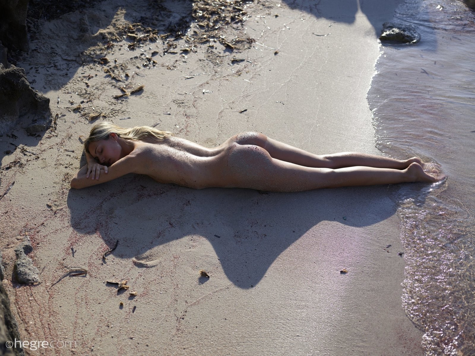 Тощая девушка в песке на пляже - фото