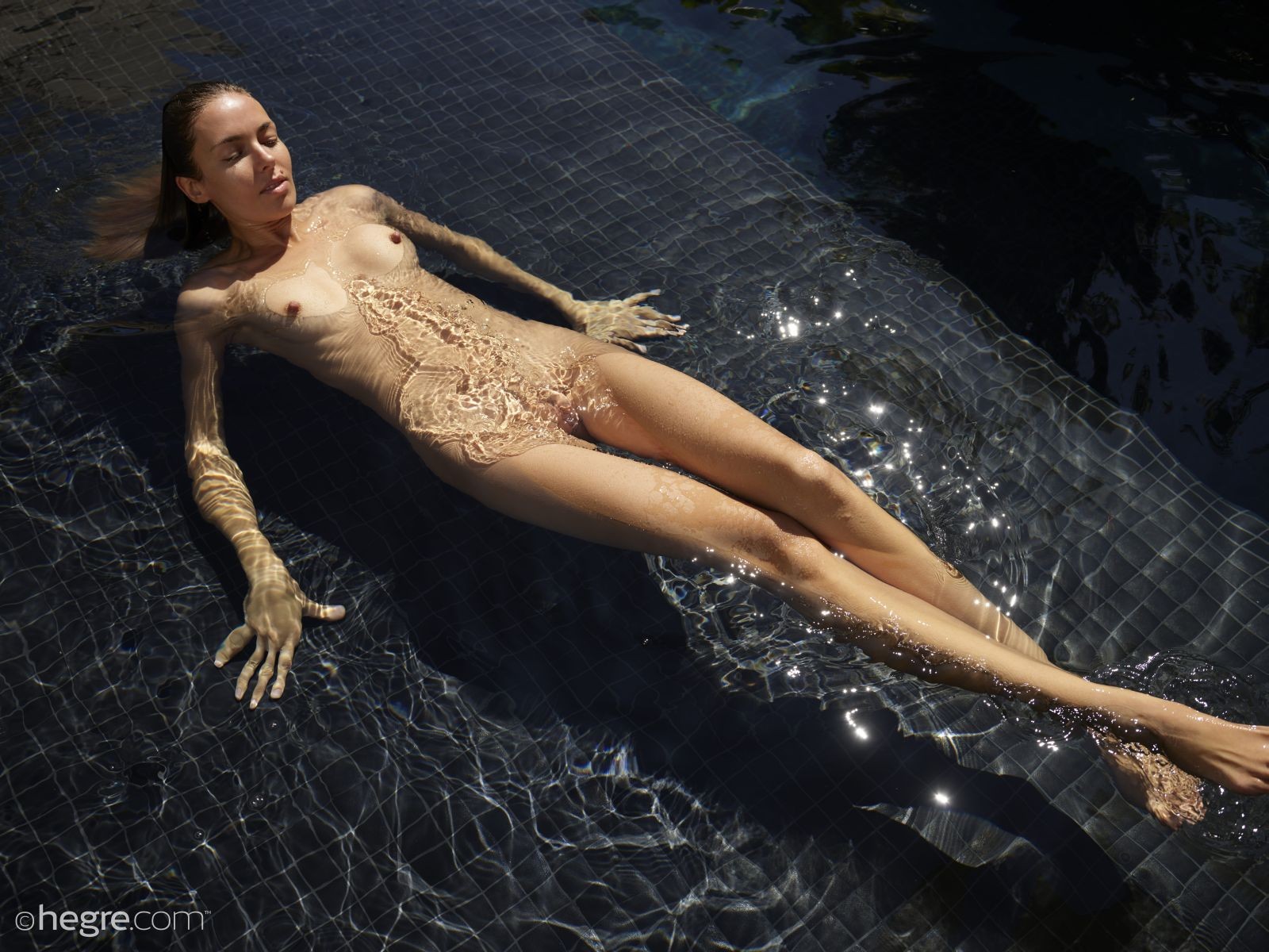 Голая девица плавает в бассейне - фото