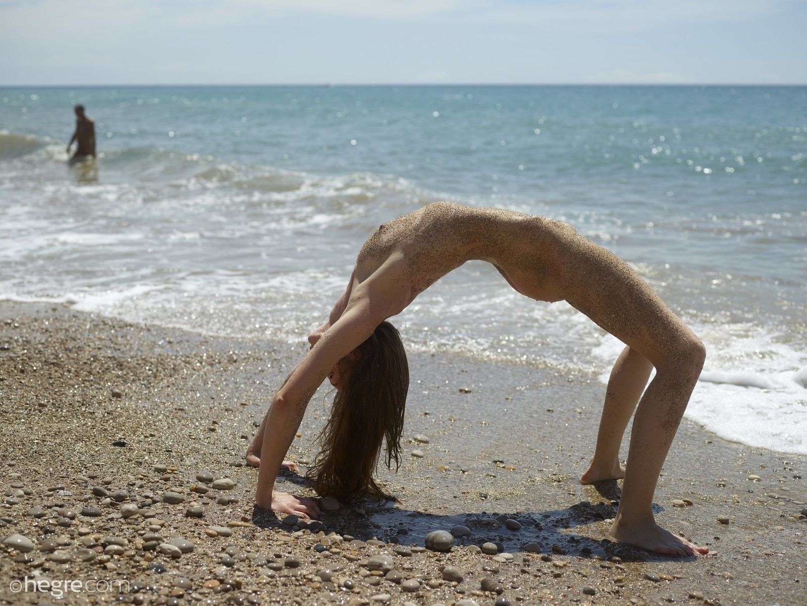 Голая нудистка в песке на пляже - фото