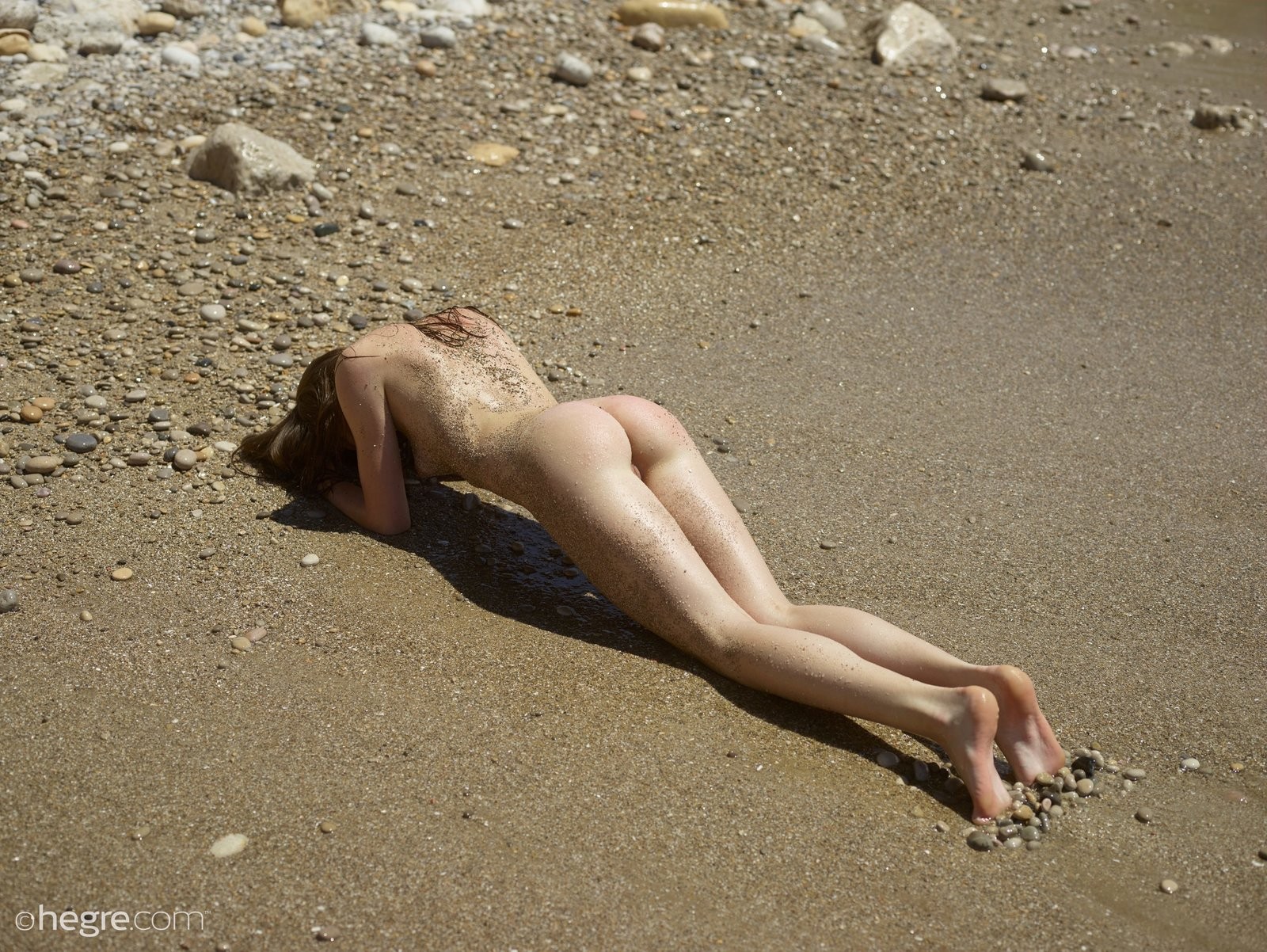 Голая нудистка в песке на пляже - фото